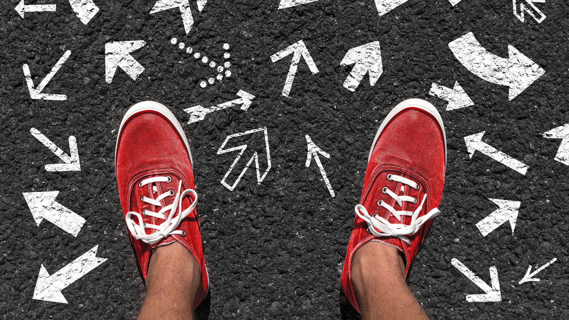 Person mit roten Sneakers steht auf Asphalt mit vielen weißen Pfeilen in unterschiedliche Richtungen als Symbol für Reflexion im OKR-Zyklus.