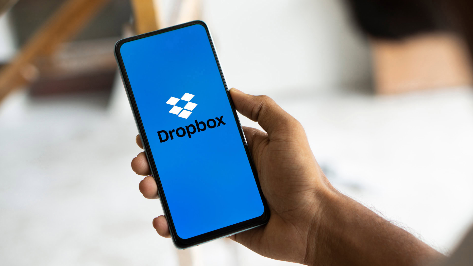 Hand hält ein Smartphone mit geöffneter Dropbox-App auf blauem Bildschirm. Dropbox wird als Beispiel für ein Minimum Viable Product betrachtet, das mit einem simplen Erklärvideo getestet wurde, bevor die eigentliche Entwicklung begann.