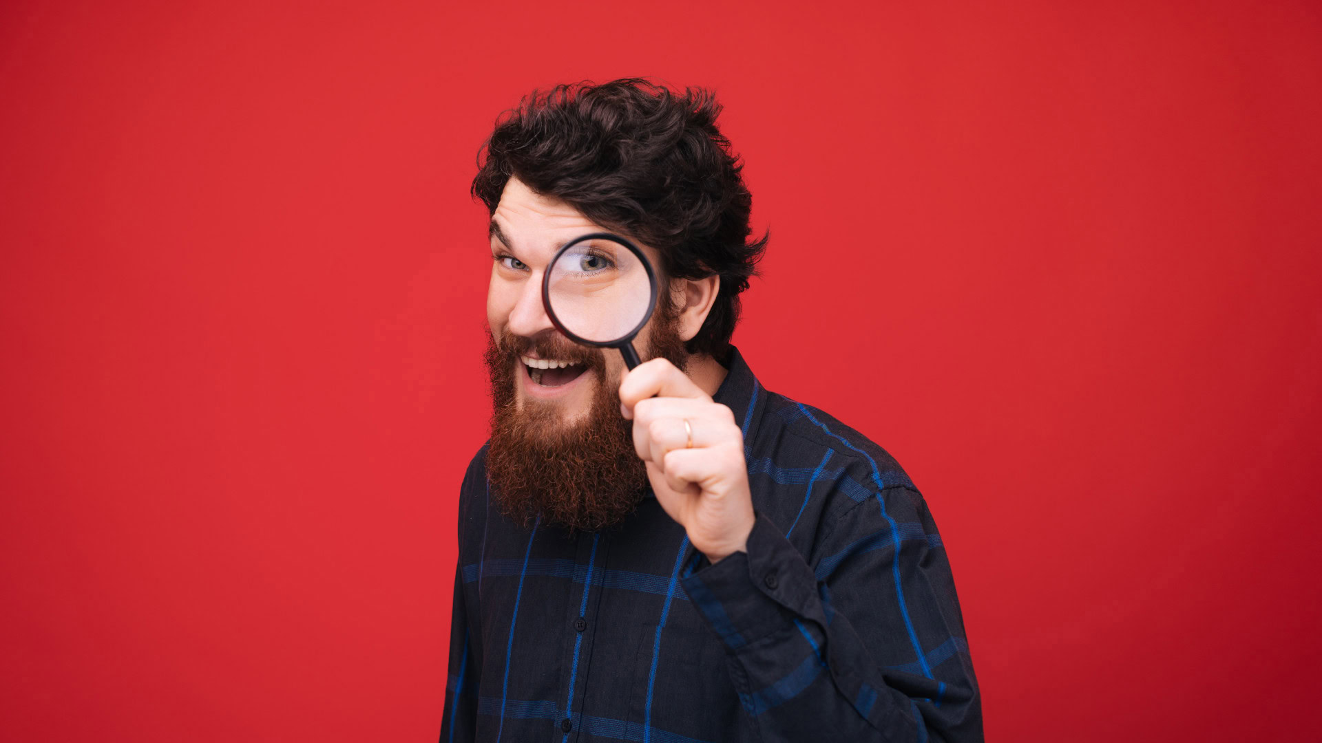 Ein Mann mit Bart und Brille hält eine Lupe vor sein Auge und schaut neugierig – ein Sinnbild für die Suche nach Early Adoptern, die als erste neue Innovationen entdecken und testen.