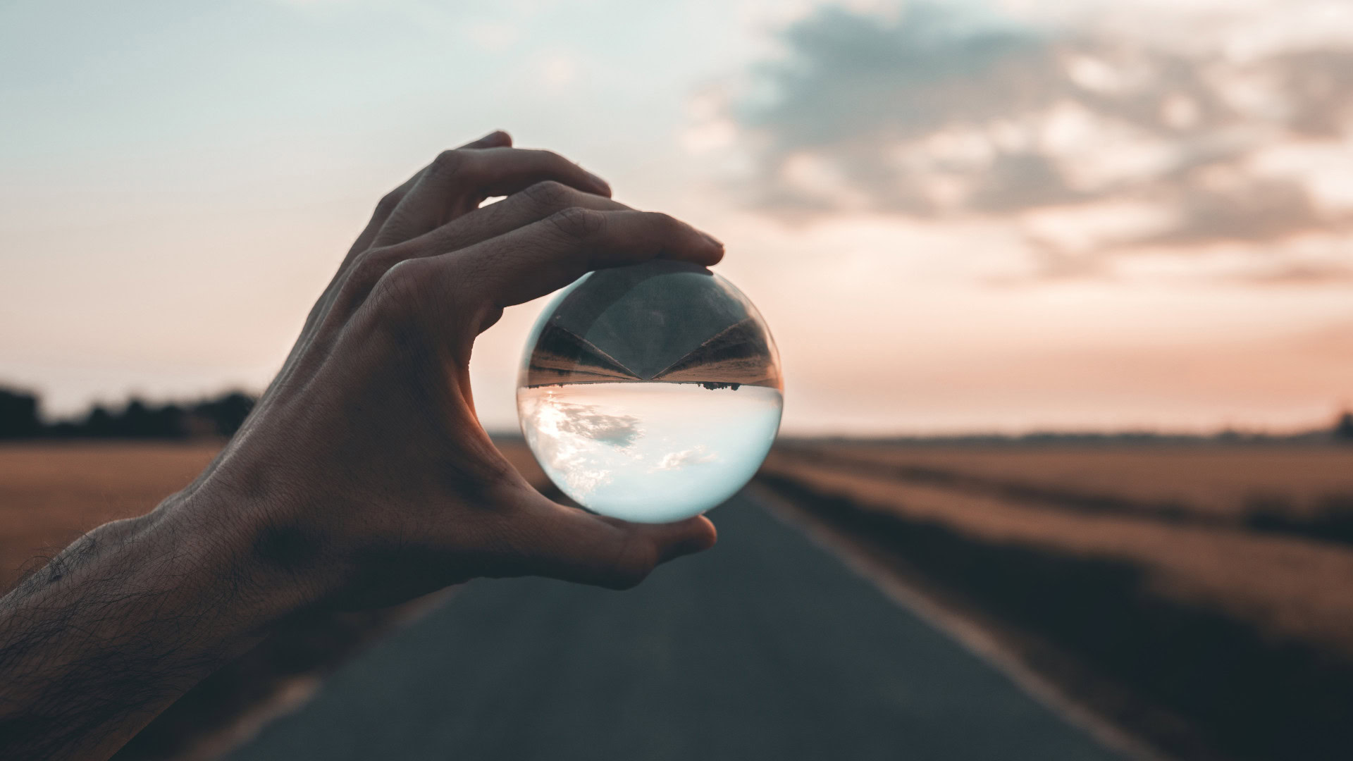 Eine Hand hält eine Glaskugel vor eine Landstraße. Das Bild steht für eine veränderte Perspektive – ein zentrales Element von Effectuation, dem Ansatz, mit vorhandenen Ressourcen neue Möglichkeiten zu schaffen.