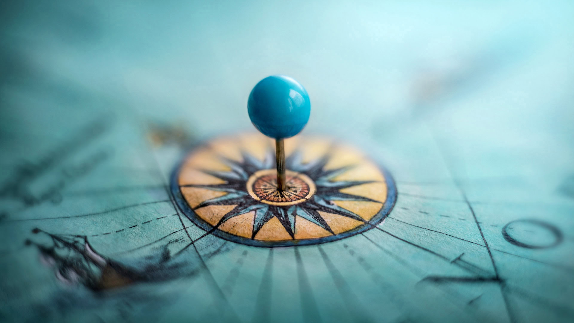 Blauer Stecknadelkopf auf einer detaillierten Kompassrose als Symbol für Orientierung und strategische Flexibilität mit Fokus auf ein klares Moal (Midterm-Goal).
