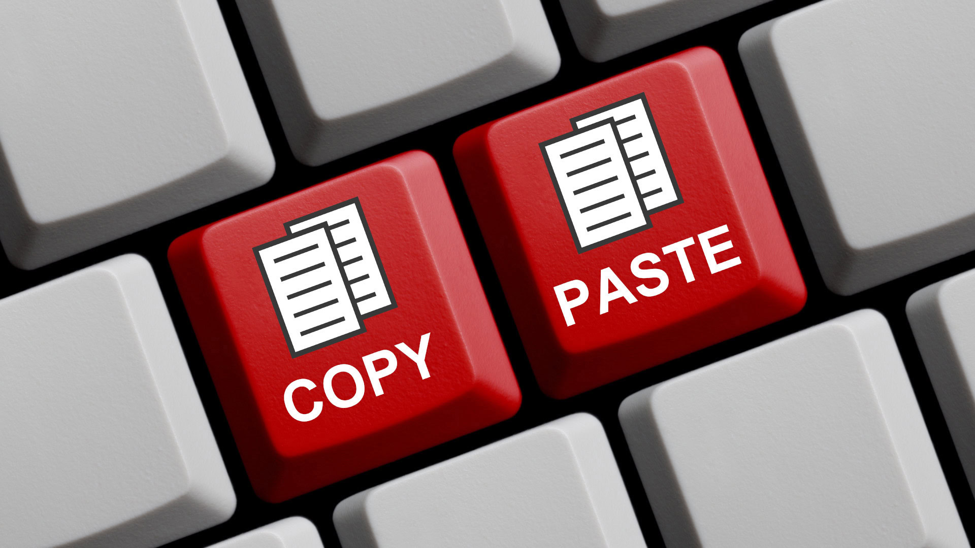 Nahaufnahme einer Tastatur mit zwei auffälligen roten Tasten, die mit "COPY" und "PASTE" beschriftet sind. Beide Tasten zeigen zudem ein Symbol mit übereinanderliegenden Dokumenten.