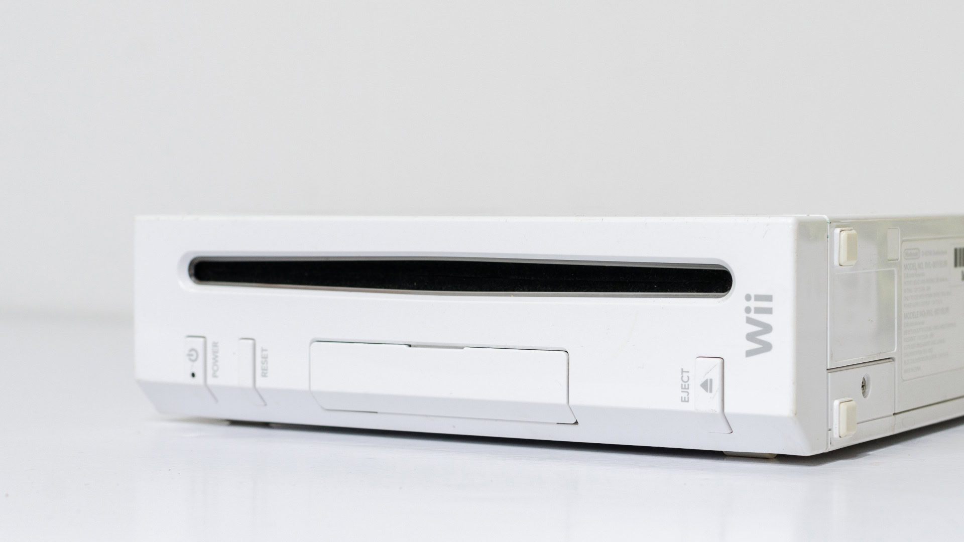 Eine Nintendo Wii in Weiß, liegend auf einer weißen Oberfläche vor einem neutralen Hintergrund. Die Vorderseite der Konsole ist zu sehen, mit dem schmalen schwarzen Disc-Schlitz in der Mitte, darunter die Power-, Reset- und Eject-Tasten. Auf der rechten Seite befindet sich das silbergraue "Wii"-Logo. Diese Konsole gilt als Beispiel für die Blue-Ocean-Strategie, da Nintendo mit der Wii eine neue Zielgruppe erschloss, indem sie auf eine innovative Bewegungssteuerung setzte, anstatt sich auf reine Grafikleistung zu konzentrieren.