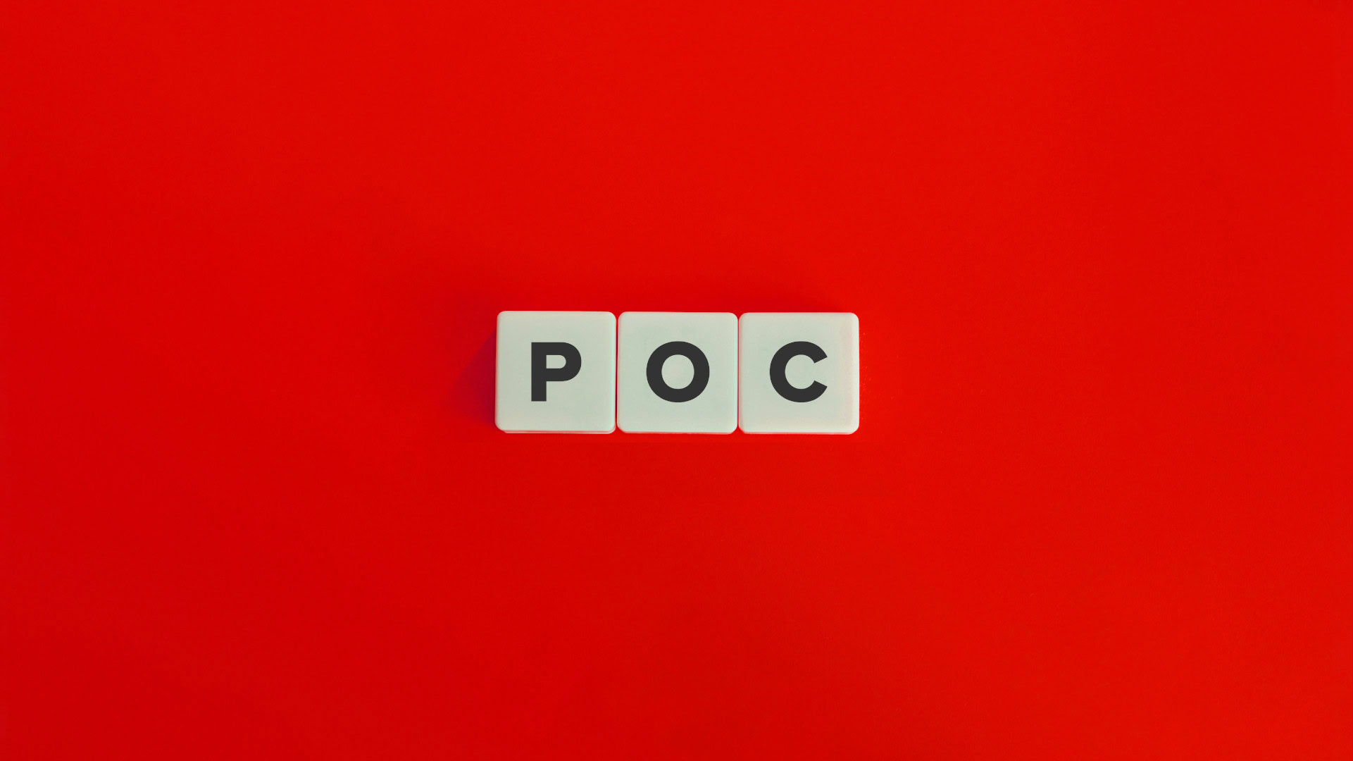 3 Scrabblesteine auf rotem Hintergrund bilden das Akronym POC für Proof of Concept.