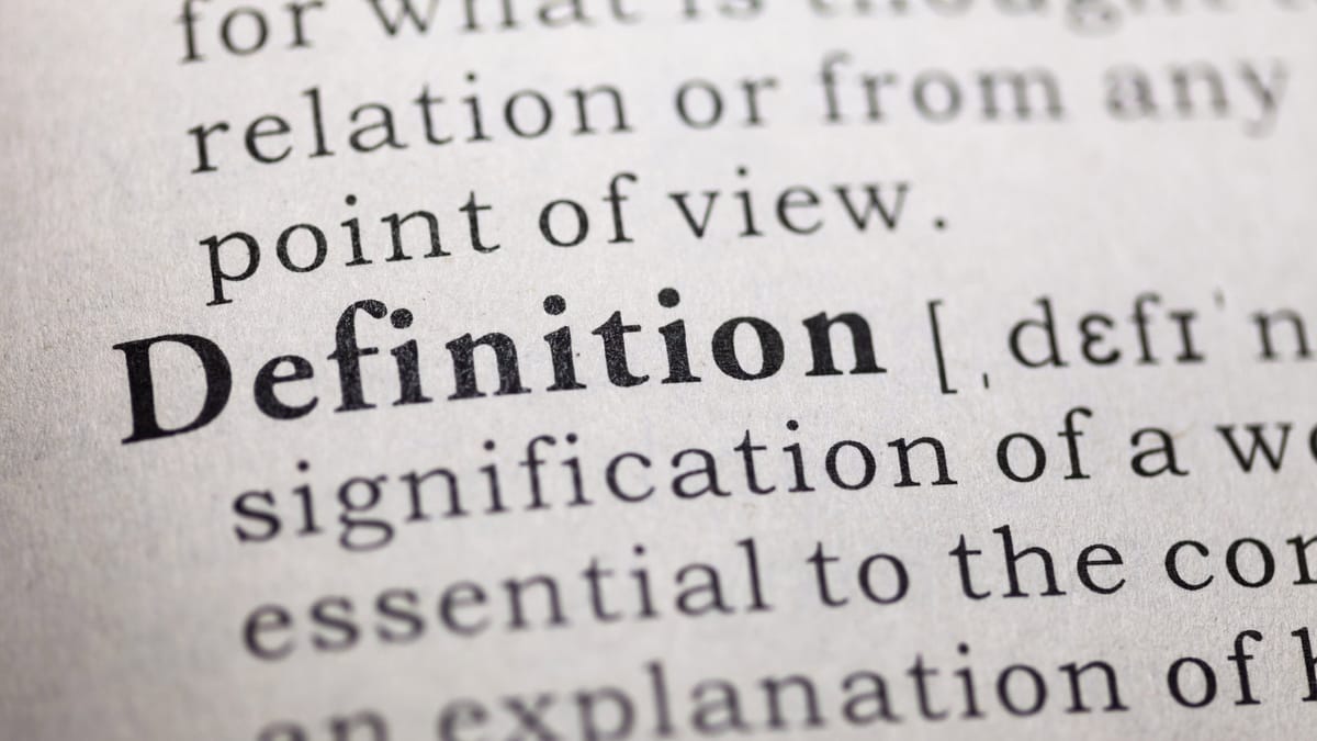 Nahaufnahme einer Buchseite mit dem fettgedruckten Wort "Definition", gefolgt von einer phonetischen Umschrift und weiteren E