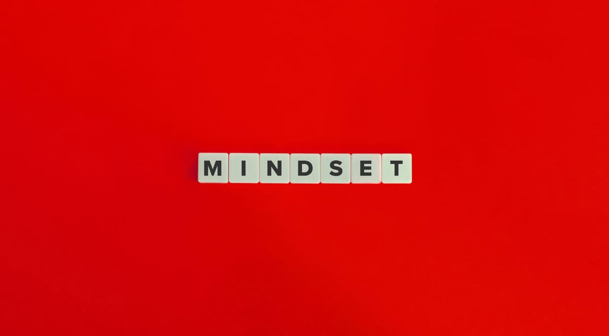 Weiße Buchstabensteine bilden das Wort Mindset auf einem roten Hintergrund. Dies symbolisiert das Design Thinking Mindset, da