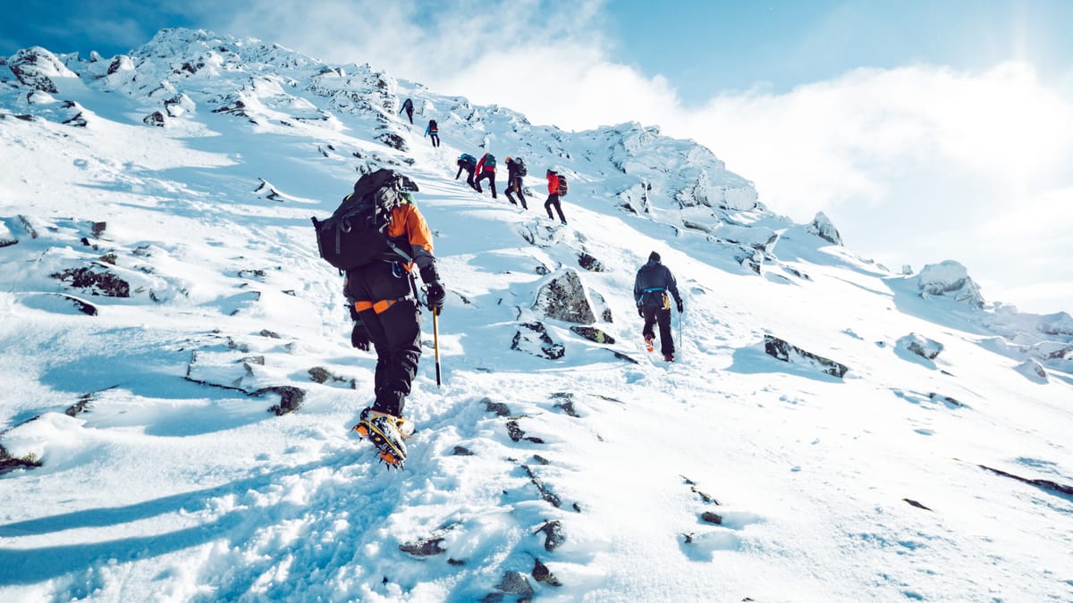 Eine Bergsteigergruppe auf dem Weg zum schneebedeckten Gipfel.
