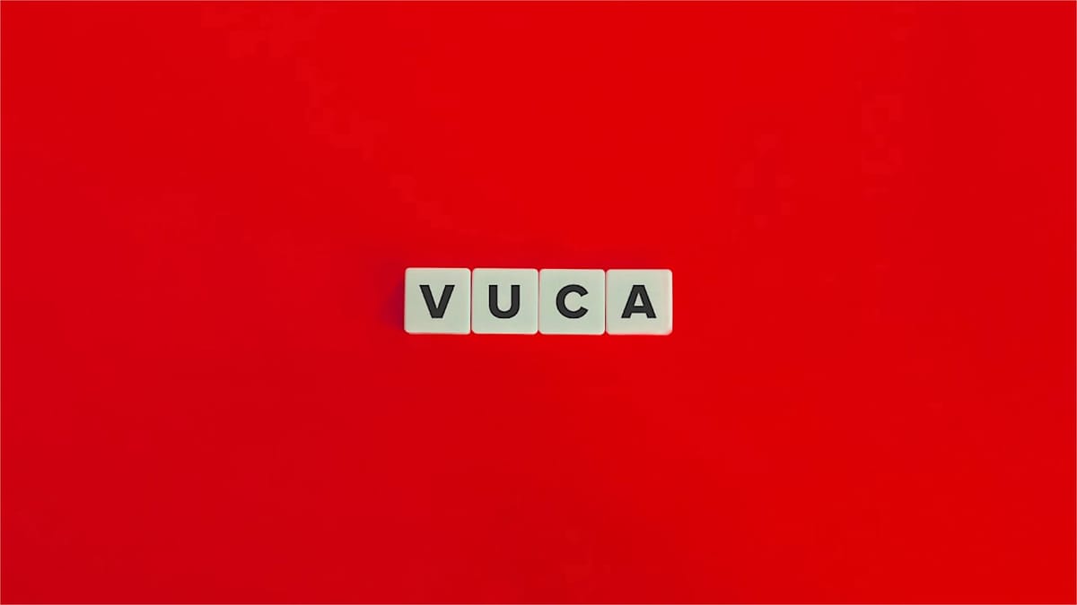 Vier weiße Buchstabenwürfel mit der Aufschrift "VUCA" liegen auf einem roten Hintergrund. VUCA steht für "Volatility, Uncerta