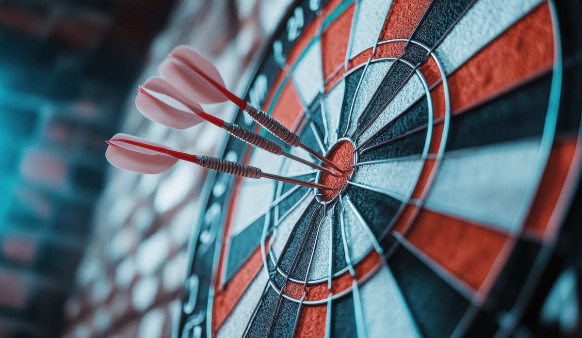 Nahaufnahme einer Dartscheibe^, in deren Bullseye drei rote Dartpfeile stecken