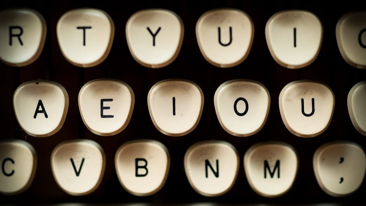 Nahaufnahme von Schreibmaschinen-Tasten. Die mittlere Reihe zeigt die Buchstaben AEIOU nebeneinander.